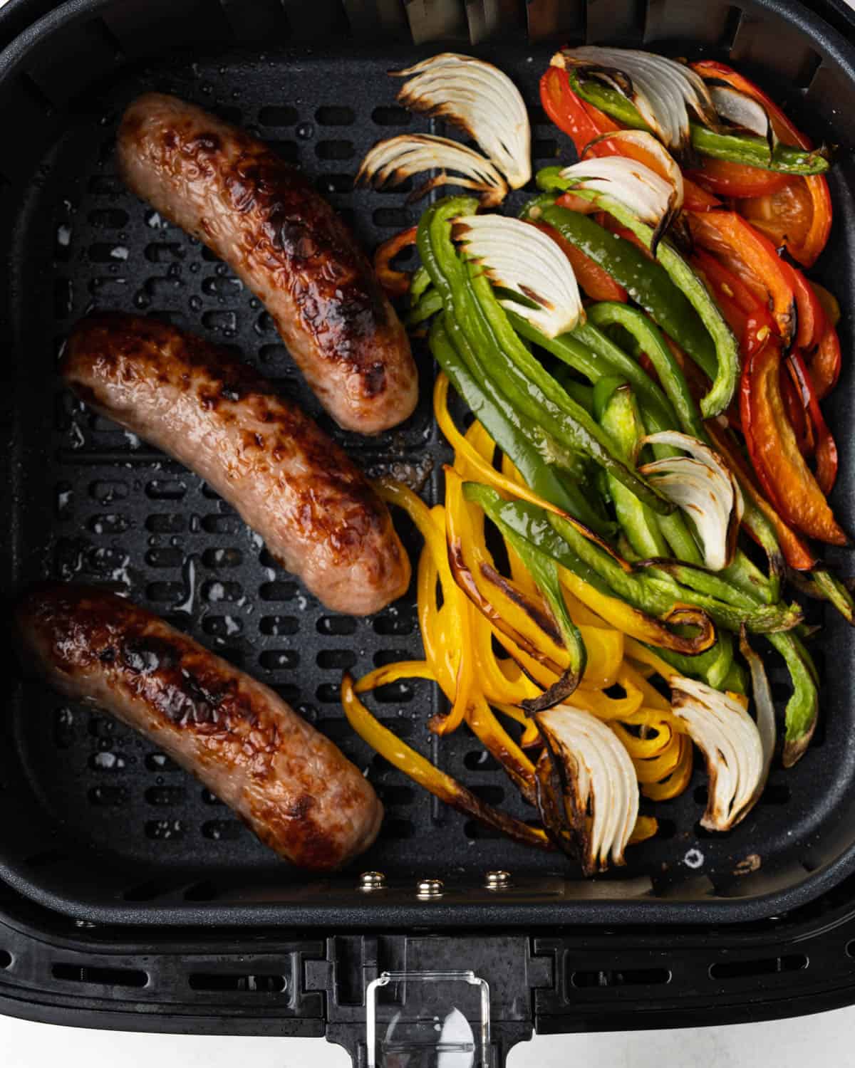 Air fried brats, onions and peppers in the air fryer basket