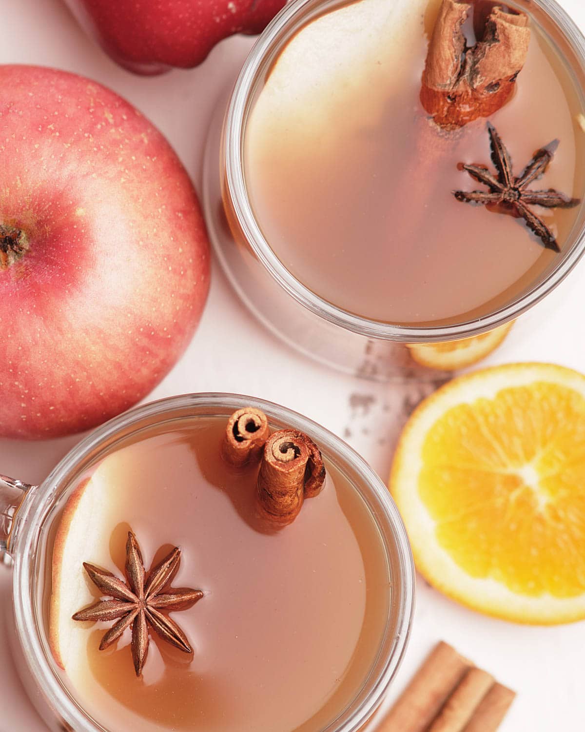 cups of instant pot apple cider with ingredients surrounding