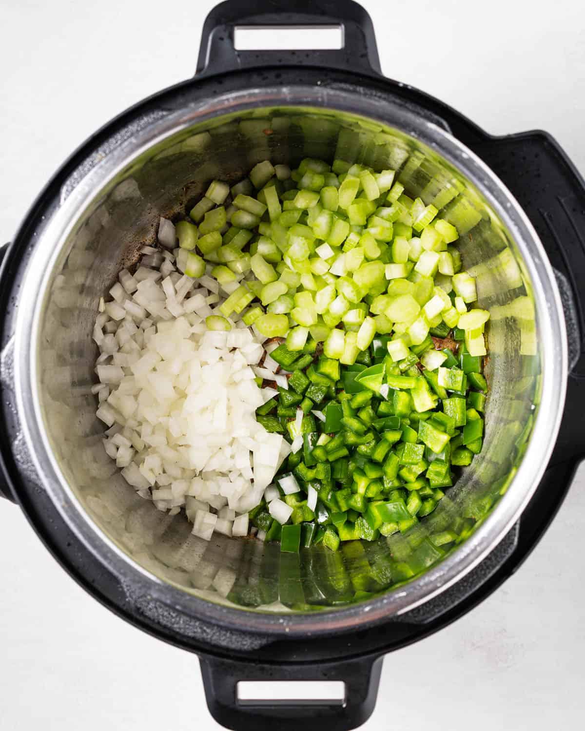 Sautéing onions, green bell peppers, and celery in the instant pot.