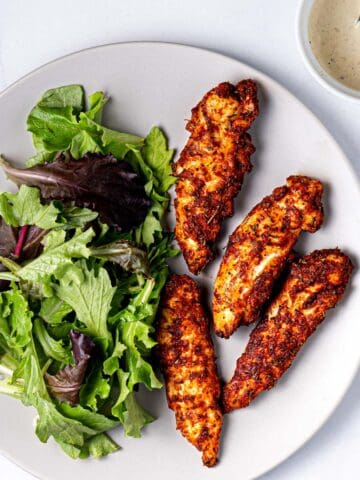 air fryer chicken tenders on a plate with a side of salad.
