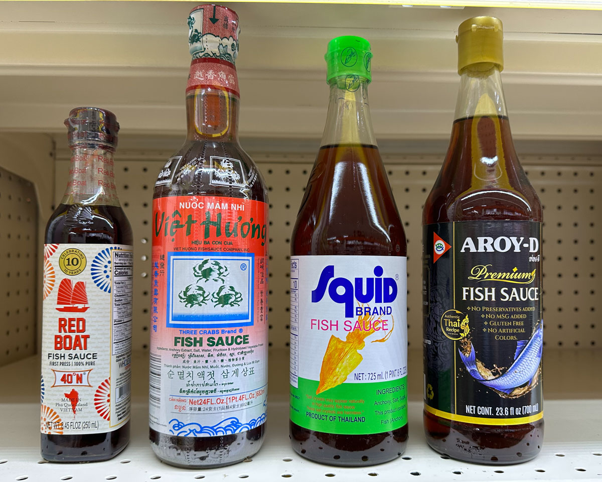 4 different bottles of fish sauce: red boat brand, three crabs brand, squid brand, and aroy-d premium brand.