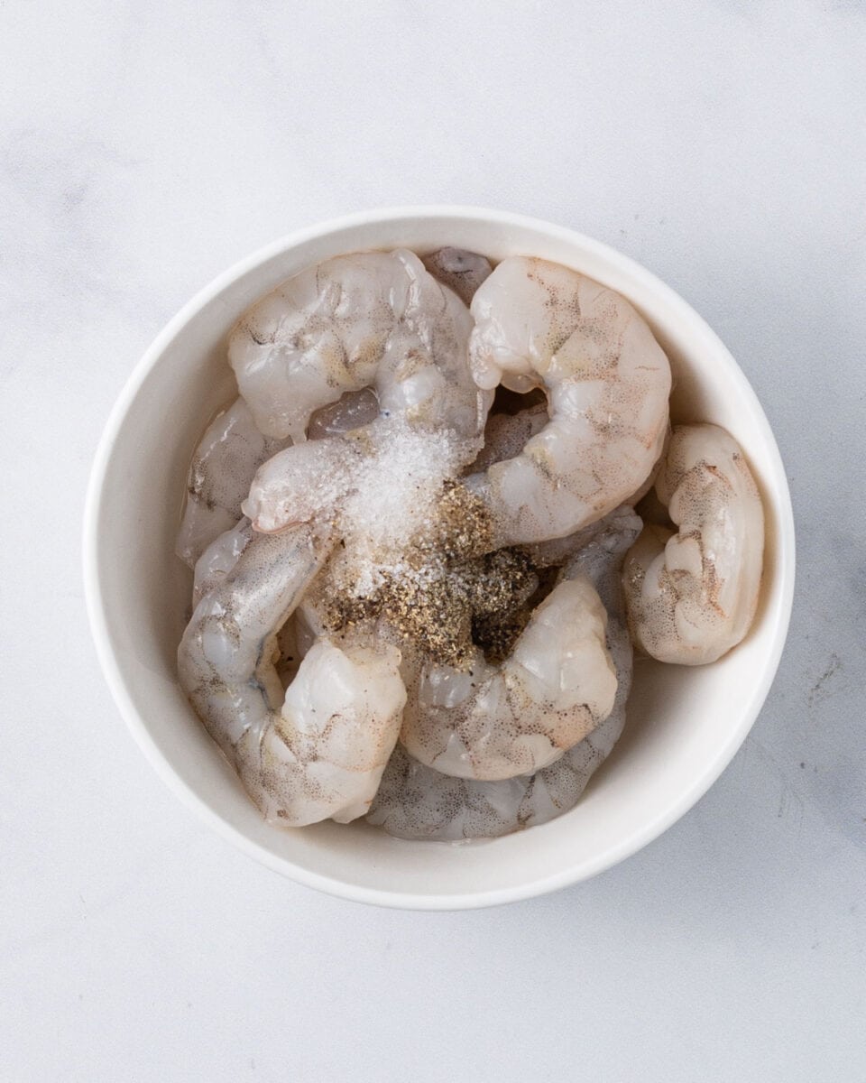 Bowl of shrimp with salt and pepper added to marinate.