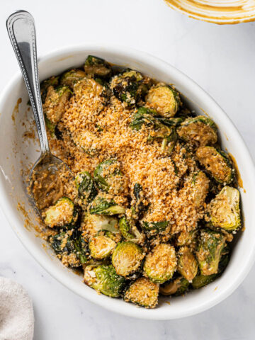 Serving dish of air fryer Brussel sprouts in a miso glaze with crunchy breadcrumbs.