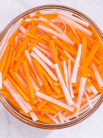 Pickled carrots and daikon in a glass bowl.