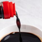 bottle pouring dark soy sauce into bowl.