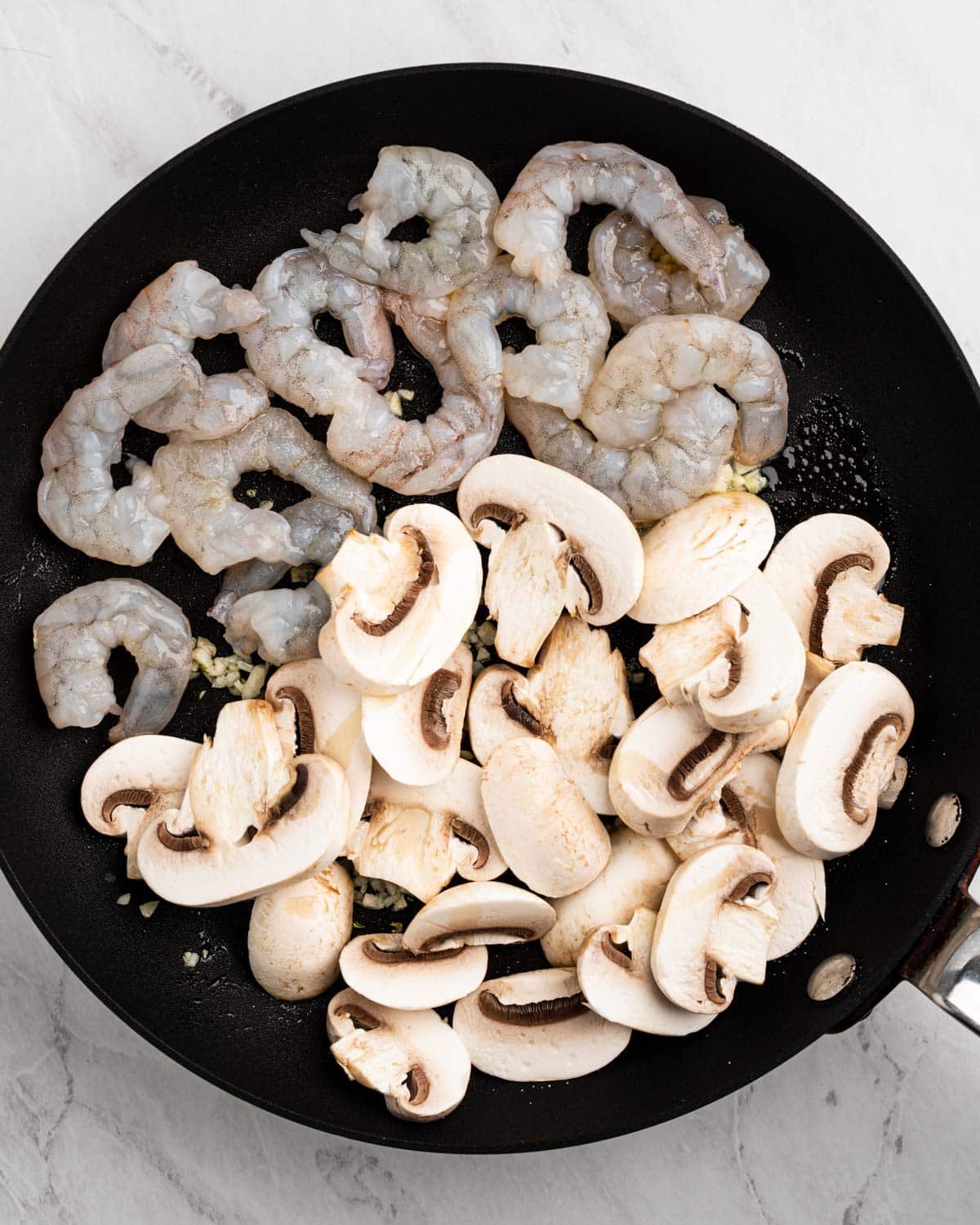 Pan sautéing mushrooms, shrimp, and garlic.