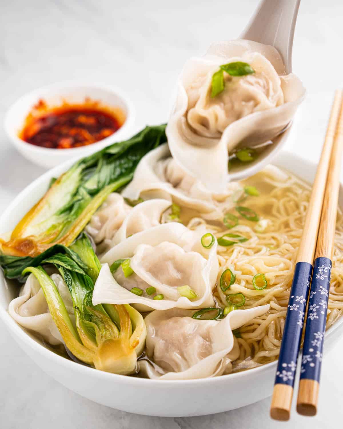 spoon scooping up wonton and broth.