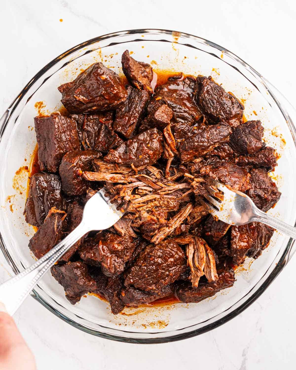 Two forks shredding beef.