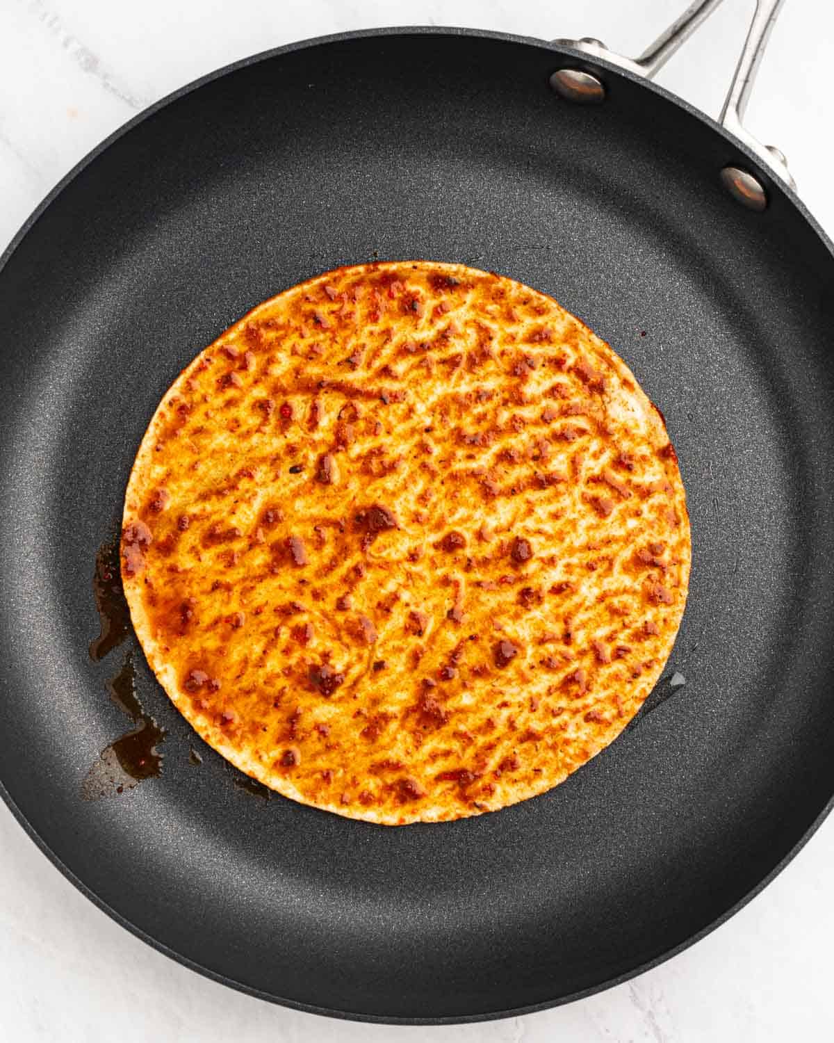 corn tortilla dipped in consommé on a pan.